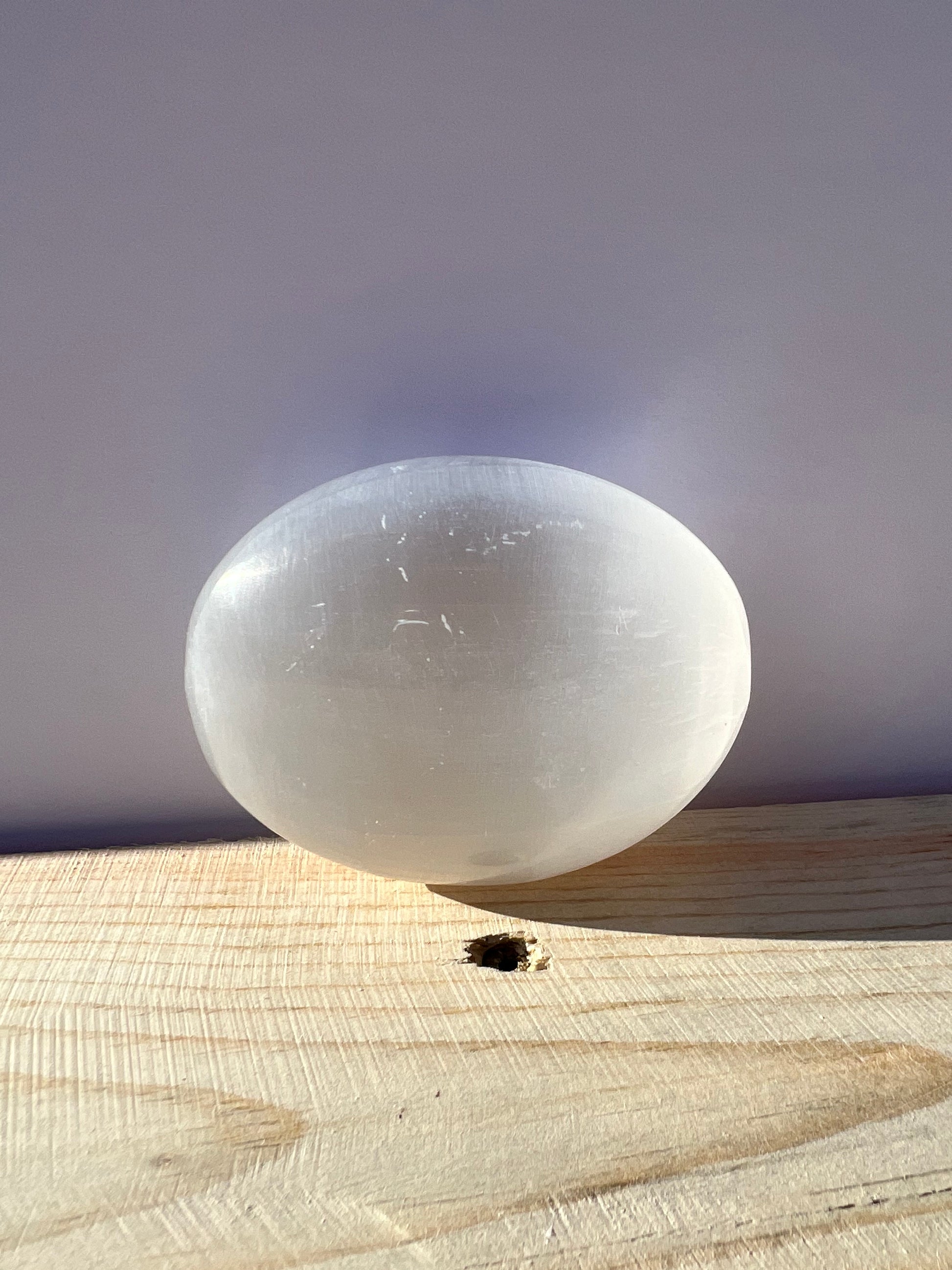 An oval shaped selenite palm stone