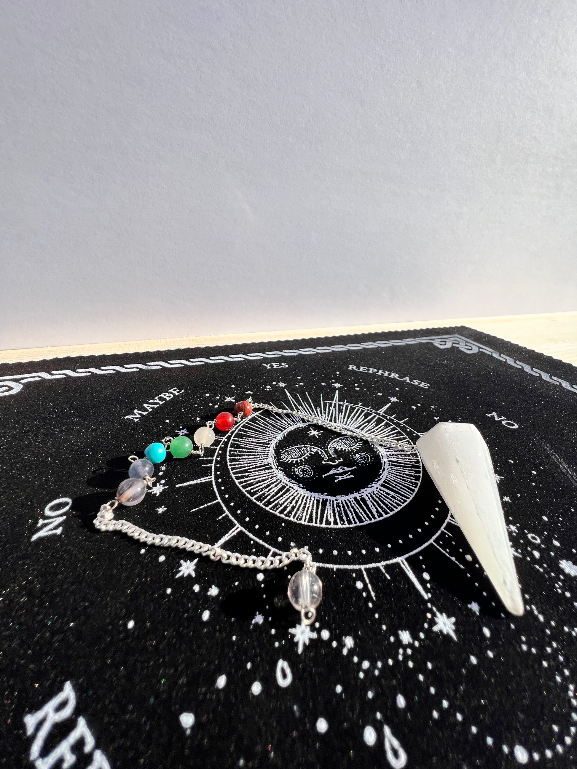 Selenite pendulum on a celestial pendulum mat