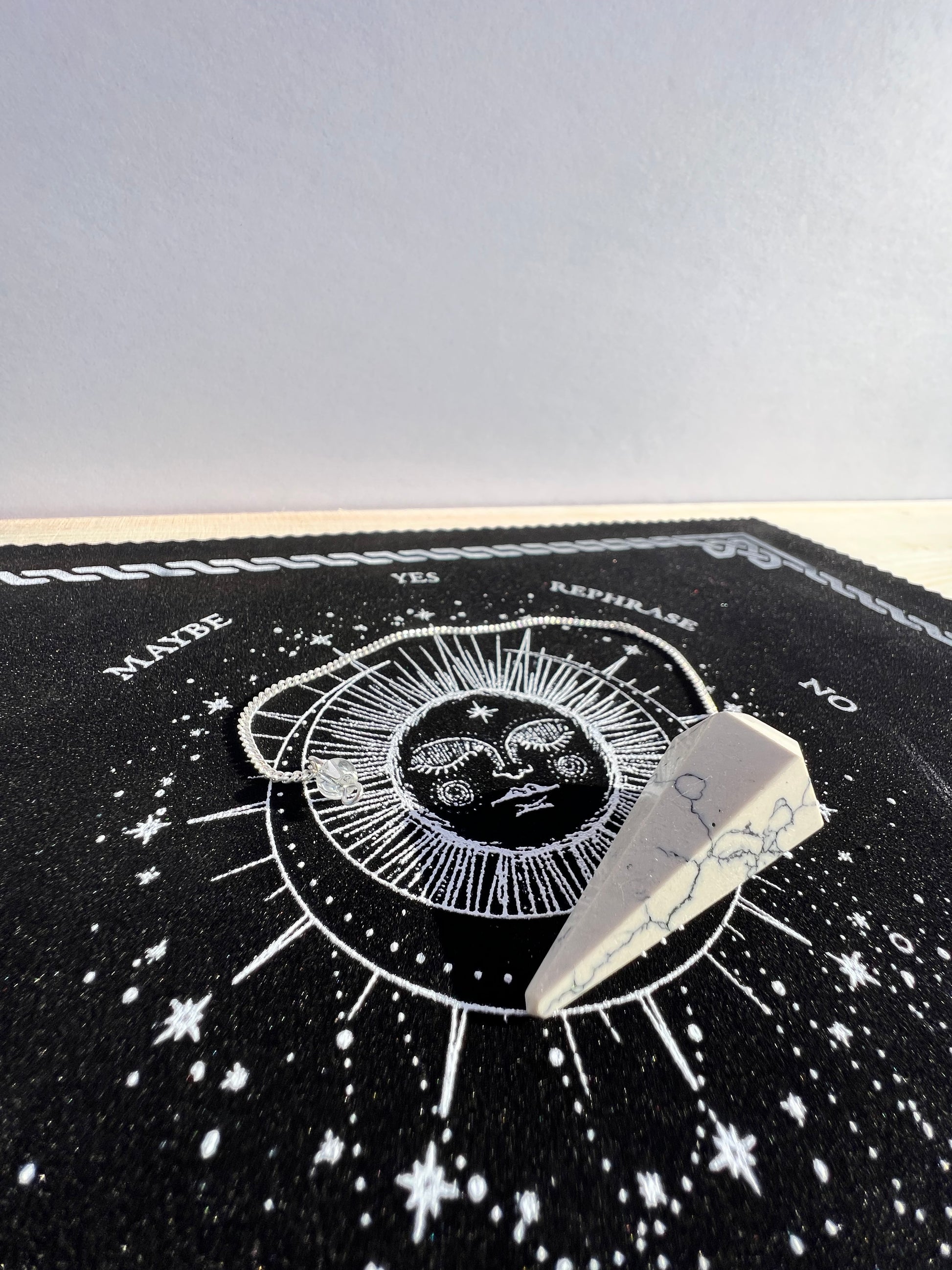 A white howlite pendulum on a celestial pendulum mat.