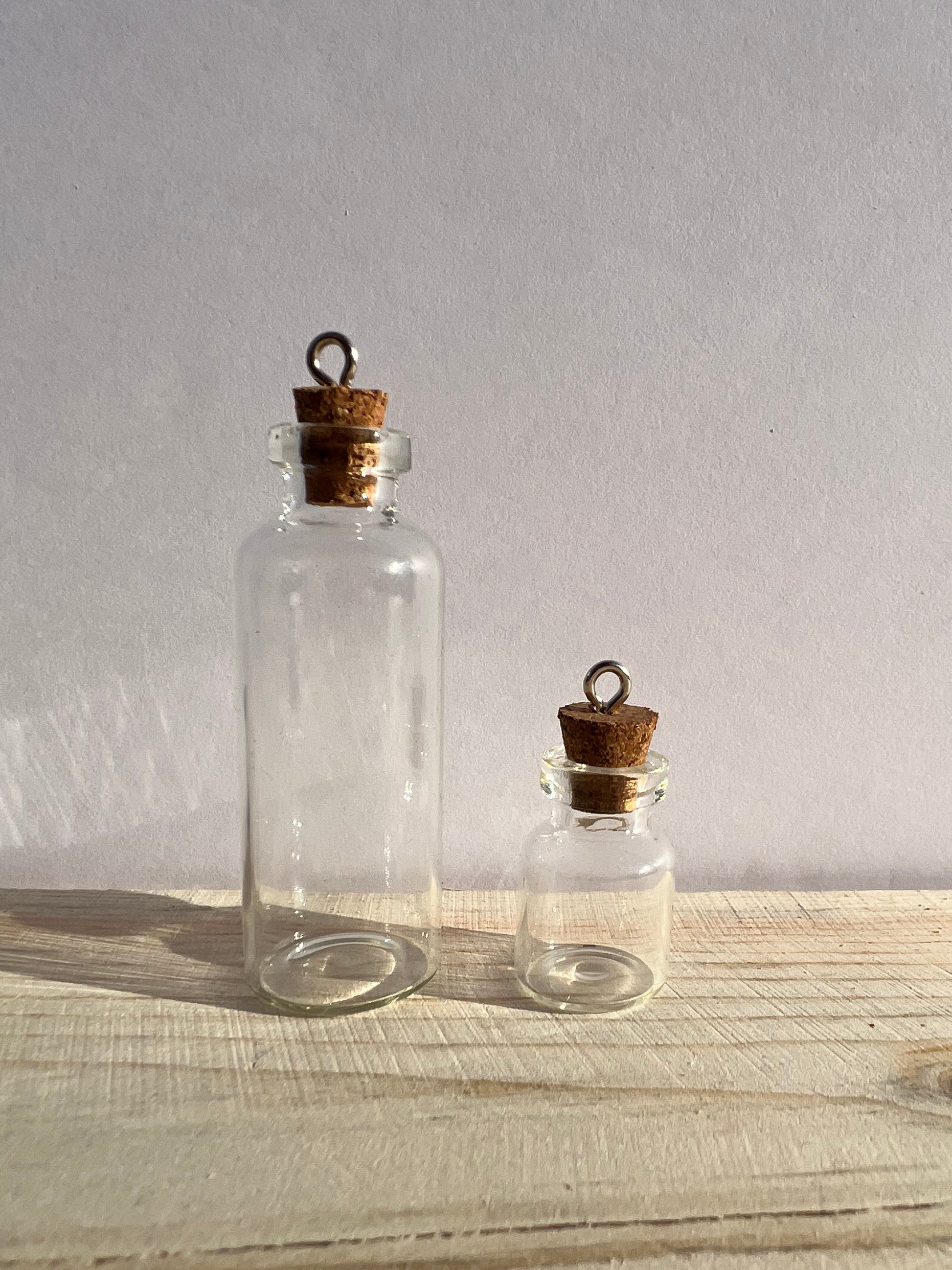 A large and small glass spell jar with eyelet hooks.